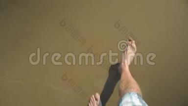 一个人的腿`在浅水中行走，在沙滩上行走